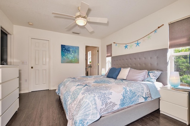 bedroom with dark wood-style floors, visible vents, baseboards, and ceiling fan