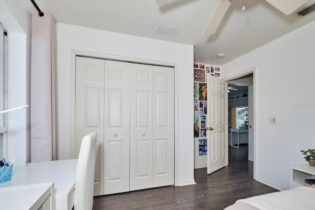 bedroom with visible vents, dark wood-type flooring, a closet, and a ceiling fan