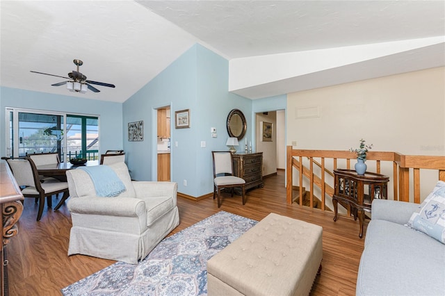 living area featuring lofted ceiling, wood finished floors, baseboards, and ceiling fan