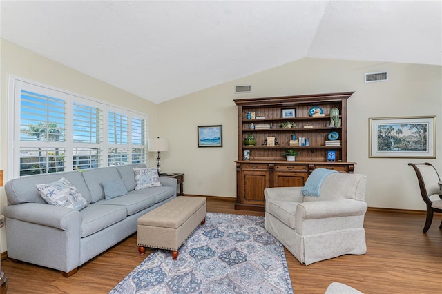 living room featuring vaulted ceiling, baseboards, visible vents, and light wood finished floors