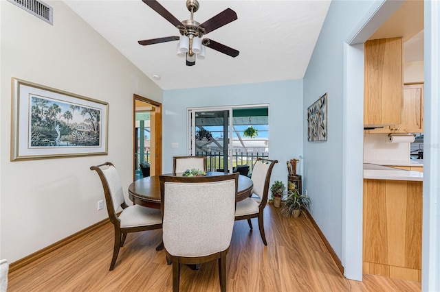 dining room featuring a ceiling fan, vaulted ceiling, light wood-style floors, and visible vents