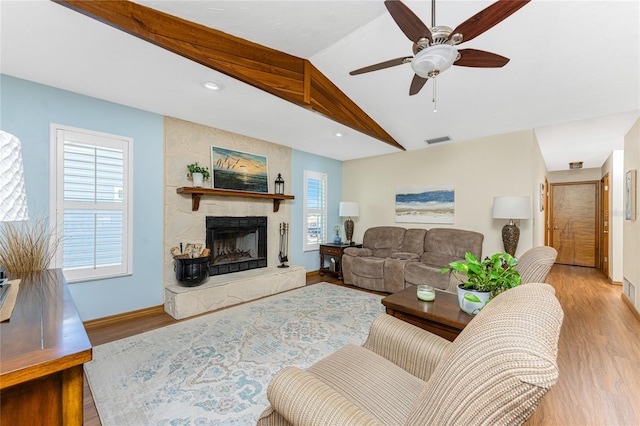 living area with a large fireplace, baseboards, lofted ceiling, wood finished floors, and a ceiling fan