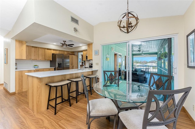 dining area with ceiling fan with notable chandelier, visible vents, light wood finished floors, and baseboards