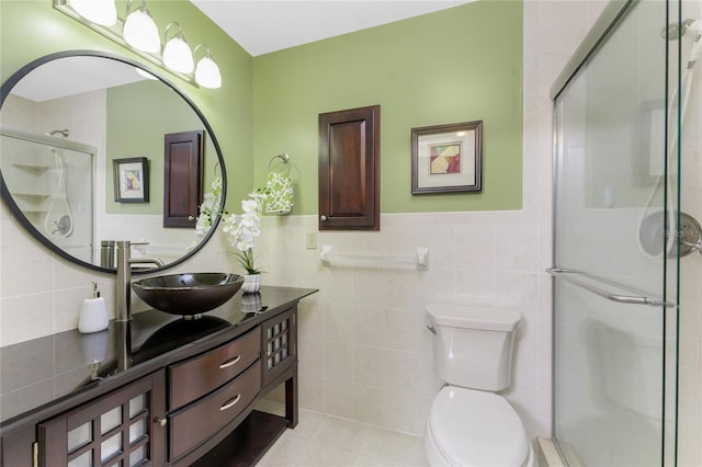 bathroom featuring vanity, a tile shower, tile patterned flooring, tile walls, and toilet