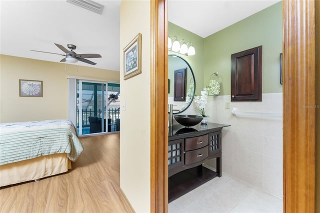 interior space with a wainscoted wall, visible vents, a sink, tile walls, and light wood-type flooring