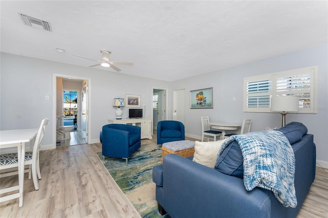 living room with visible vents, baseboards, and wood finished floors