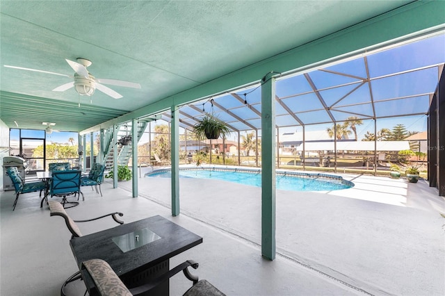 outdoor pool with glass enclosure, a patio, stairs, and ceiling fan