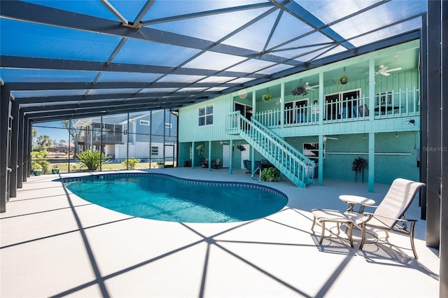 outdoor pool featuring glass enclosure, a patio, ceiling fan, and stairs