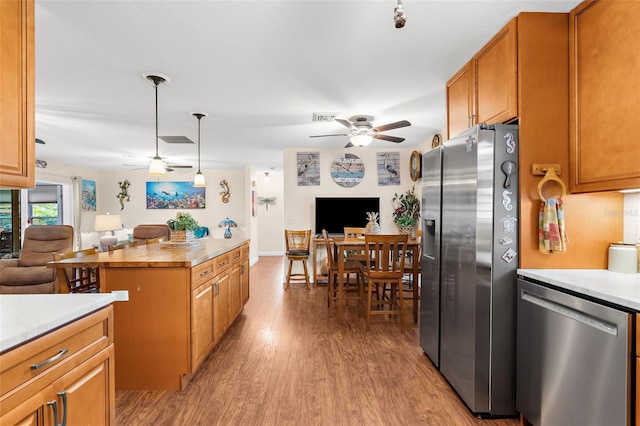 kitchen featuring visible vents, a ceiling fan, open floor plan, light wood-style floors, and appliances with stainless steel finishes