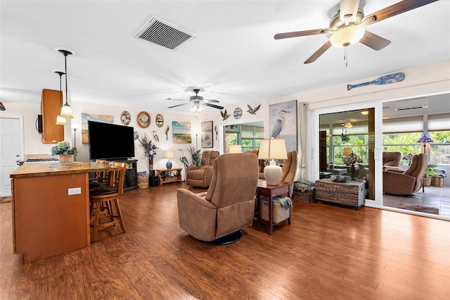 living room with an AC wall unit, wood finished floors, visible vents, and ceiling fan