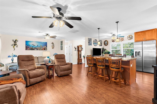 living room featuring a dry bar, wood finished floors, visible vents, and ceiling fan