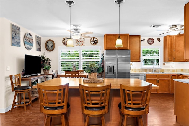 kitchen featuring visible vents, a center island, ceiling fan, appliances with stainless steel finishes, and a sink