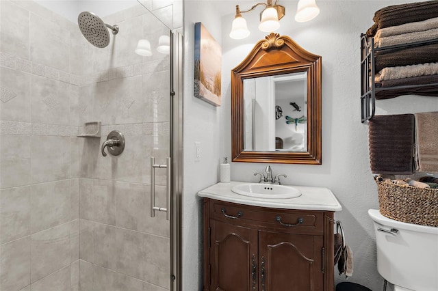 bathroom with toilet, a stall shower, and vanity