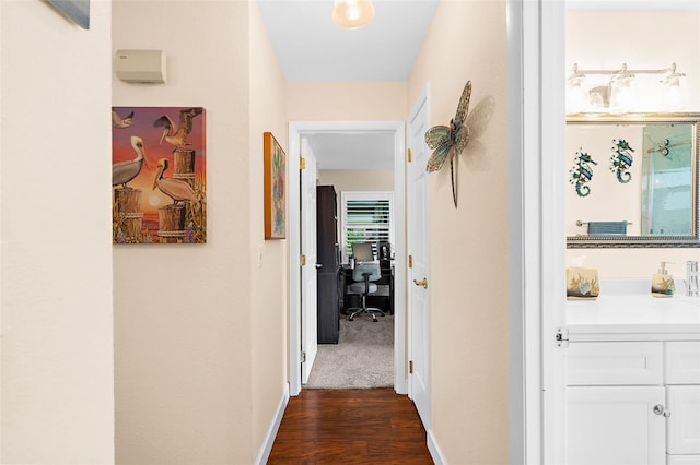 corridor featuring baseboards and dark wood-type flooring