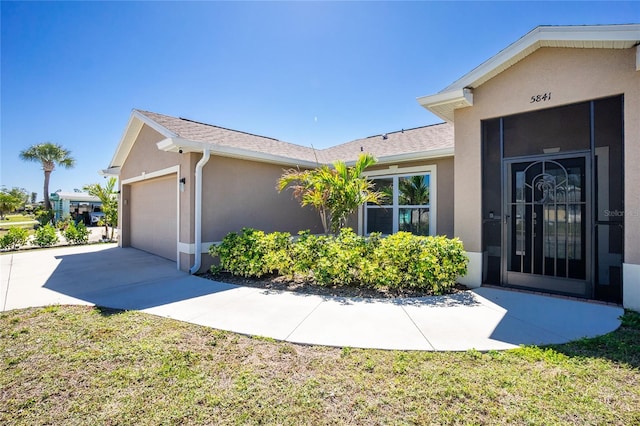 exterior space with stucco siding, roof with shingles, concrete driveway, and an attached garage