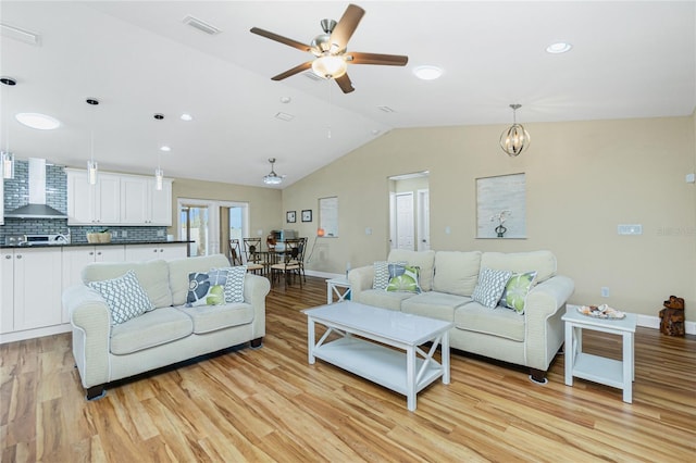 living room with visible vents, light wood-style flooring, ceiling fan with notable chandelier, baseboards, and vaulted ceiling