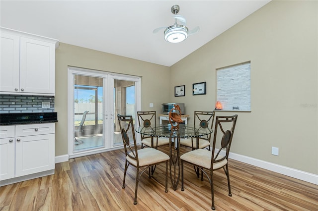 dining area featuring light wood finished floors, baseboards, and vaulted ceiling