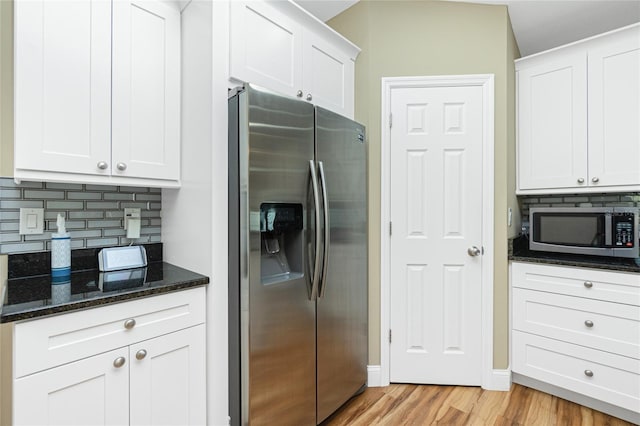 kitchen with light wood-type flooring, backsplash, white cabinetry, stainless steel appliances, and dark stone counters