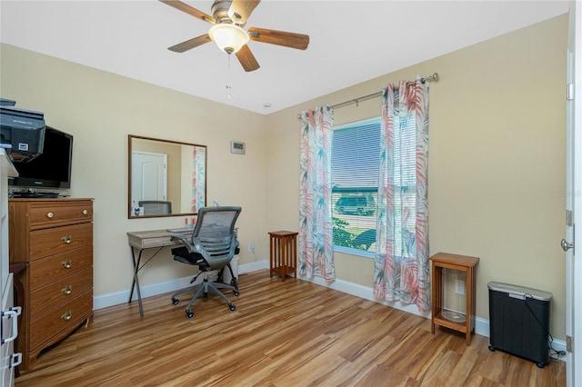 home office featuring light wood finished floors, a ceiling fan, and baseboards