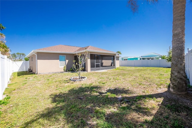 back of property with stucco siding, a lawn, a fenced backyard, and a sunroom