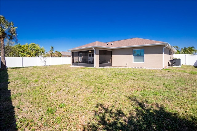 back of house with stucco siding, a lawn, a fenced backyard, and a sunroom