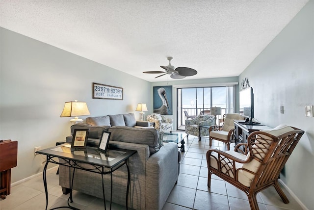 living area with a textured ceiling, light tile patterned floors, baseboards, and ceiling fan