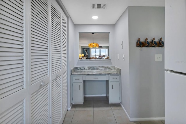 hallway featuring light tile patterned floors, visible vents, and baseboards