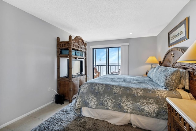 bedroom featuring baseboards, a textured ceiling, access to exterior, and light tile patterned flooring