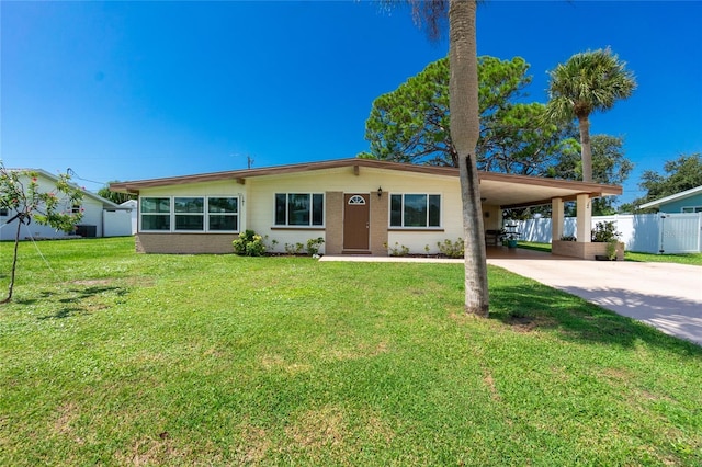 view of front of house with an attached carport, concrete driveway, a front yard, and fence