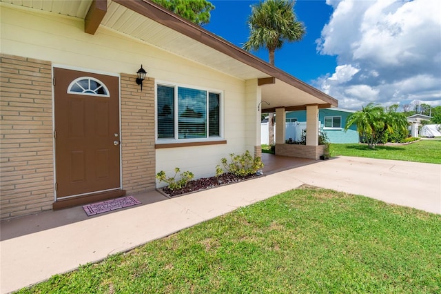 doorway to property with a yard and brick siding