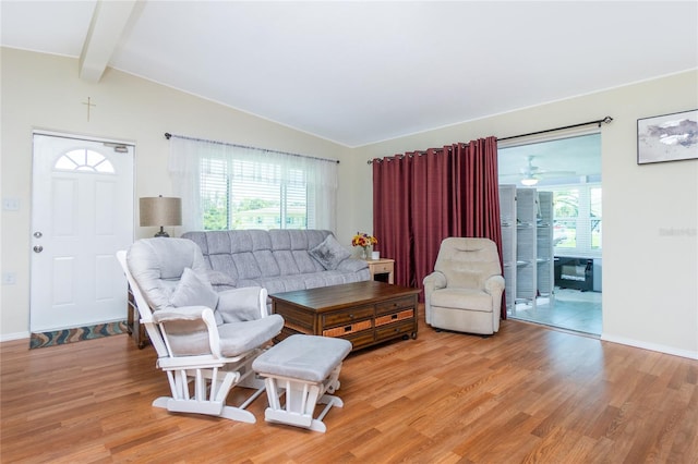 living area featuring lofted ceiling with beams, plenty of natural light, and light wood-style floors