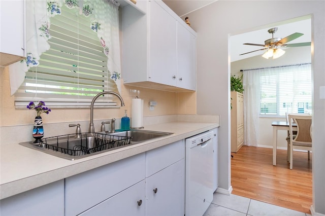 kitchen with a sink, dishwasher, white cabinets, and light countertops