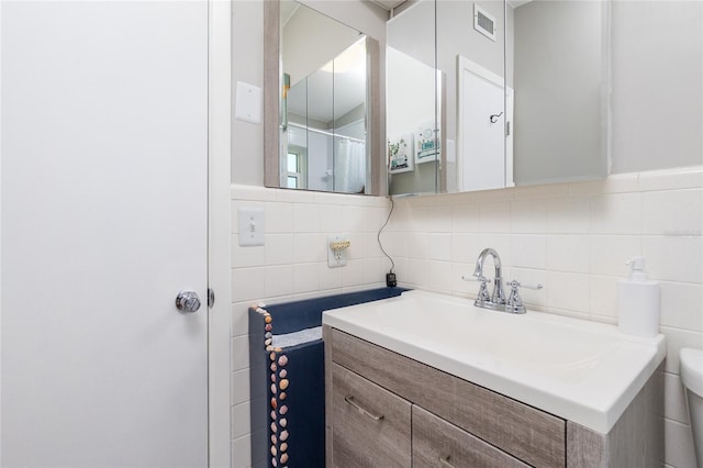 bathroom featuring visible vents, toilet, tile walls, and vanity