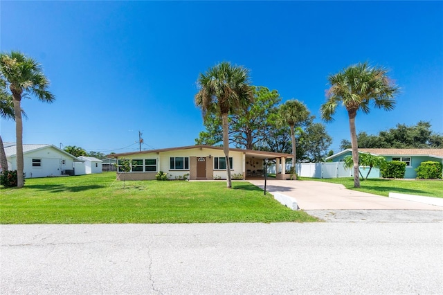 ranch-style house with an attached carport, concrete driveway, a front lawn, and fence