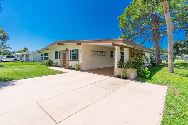 ranch-style home with concrete driveway, a carport, and a front lawn