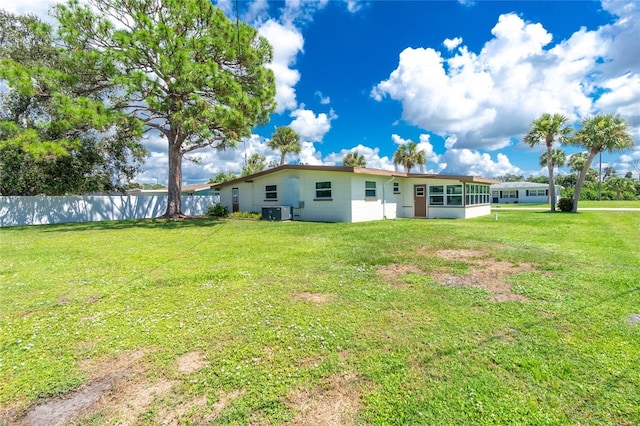 rear view of property featuring fence, a lawn, and a sunroom