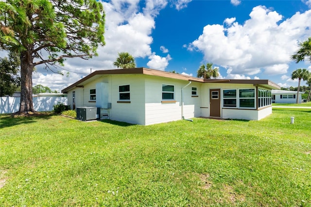 back of property featuring cooling unit, a lawn, and fence