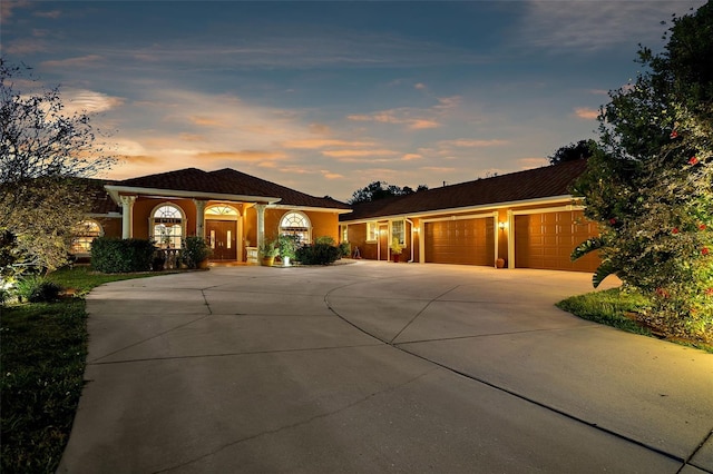 mediterranean / spanish-style house with concrete driveway, an attached garage, and stucco siding