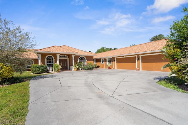 mediterranean / spanish home featuring stucco siding, a garage, and driveway