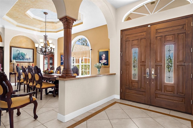 entryway with light tile patterned flooring, crown molding, a tray ceiling, and baseboards