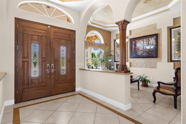 foyer featuring light tile patterned flooring, baseboards, and ornate columns