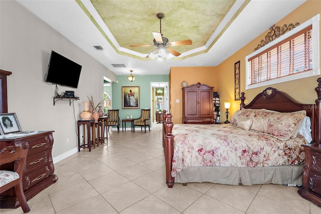 bedroom with light tile patterned floors, visible vents, multiple windows, and a tray ceiling