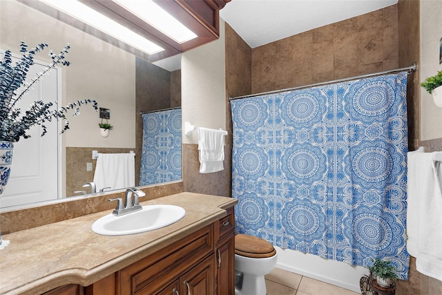 full bath featuring tile patterned flooring, tile walls, toilet, wainscoting, and vanity