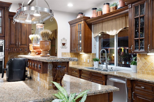 kitchen with a sink, light stone counters, backsplash, and appliances with stainless steel finishes