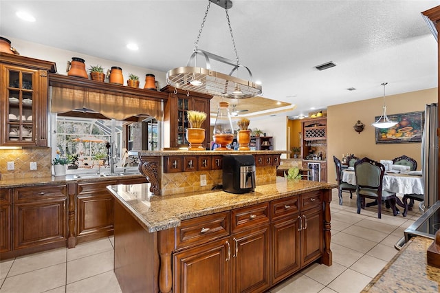 kitchen featuring light tile patterned flooring, decorative backsplash, a kitchen island, and decorative light fixtures