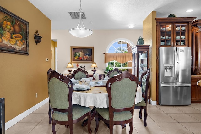 dining space featuring light tile patterned floors, visible vents, and baseboards