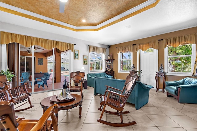 living room featuring a textured ceiling, a raised ceiling, light tile patterned flooring, and ceiling fan