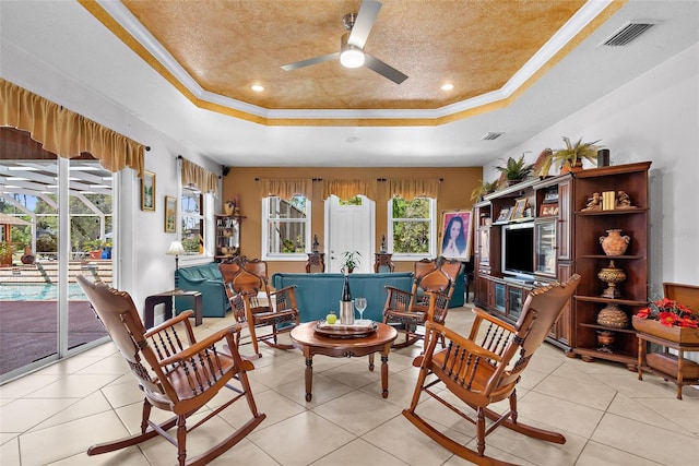 living area with visible vents, a raised ceiling, ceiling fan, and crown molding