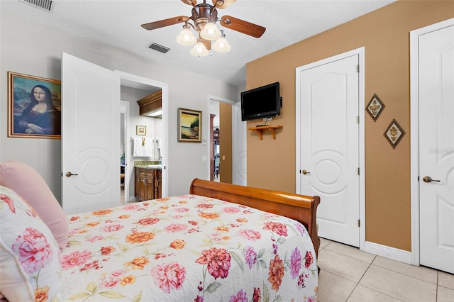 bedroom featuring visible vents, ensuite bathroom, light tile patterned floors, baseboards, and ceiling fan