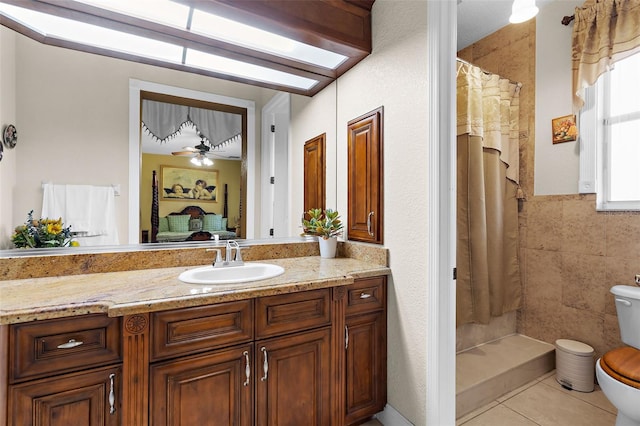 full bathroom featuring tile patterned flooring, toilet, vanity, and a tile shower